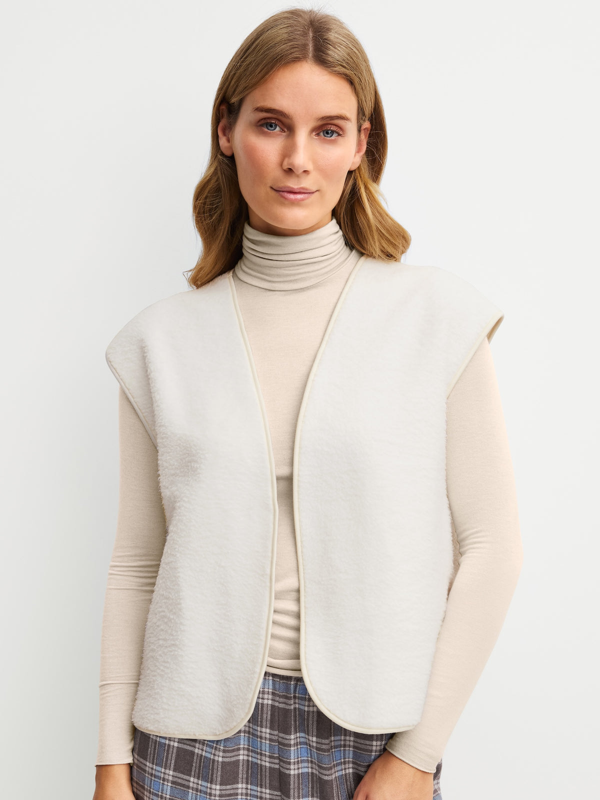 ALPINE LW‑väst i fluffigt material, stylad med polotröja för varm och avslappnad look.