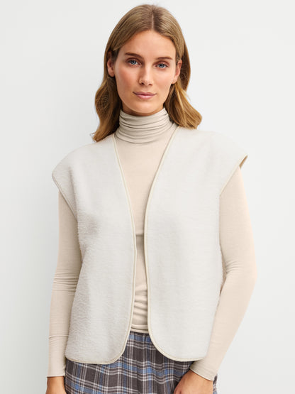 ALPINE LW‑väst i fluffigt material, stylad med polotröja för varm och avslappnad look.